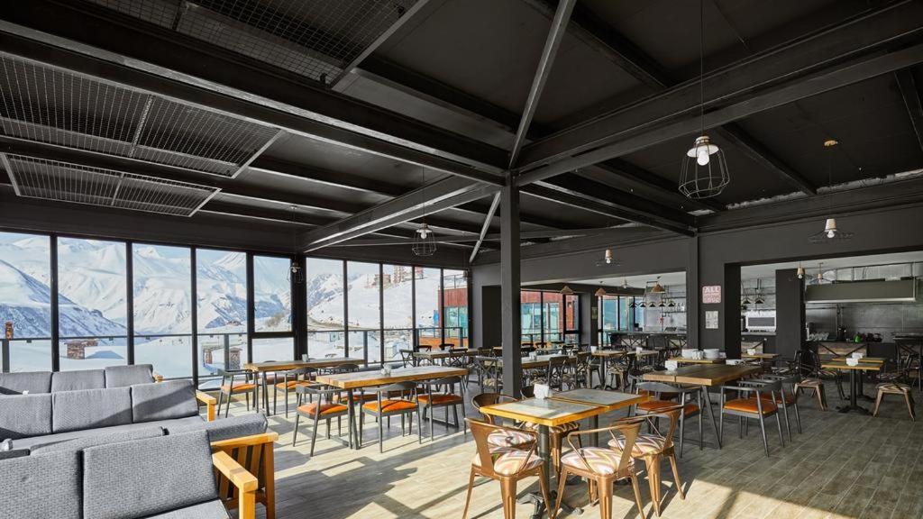 un ristorante con tavoli e sedie e montagne sullo sfondo di Gudauri Loft (Mgzavrebi) a Gudauri
