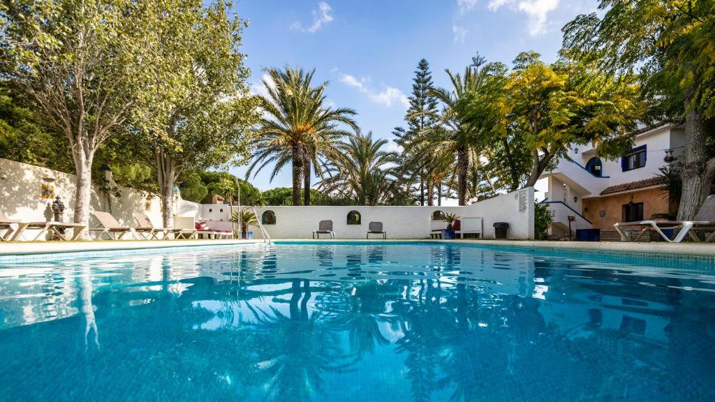 a swimming pool with trees and a white building at Paraiso Perdido in Conil de la Frontera