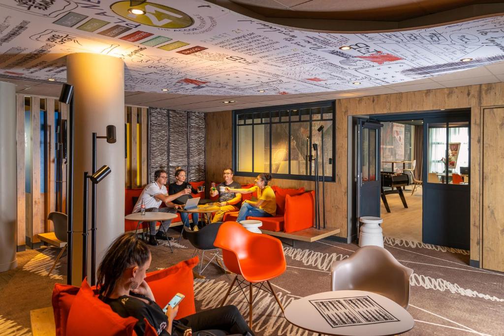 a group of people sitting in orange chairs in a room at ibis Le Havre Centre in Le Havre