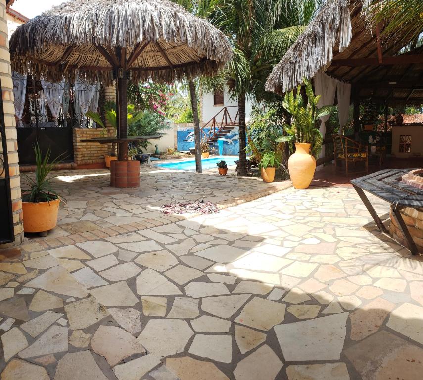 a patio with a table and a straw umbrella at Pousada Morena Moleca in Canoa Quebrada