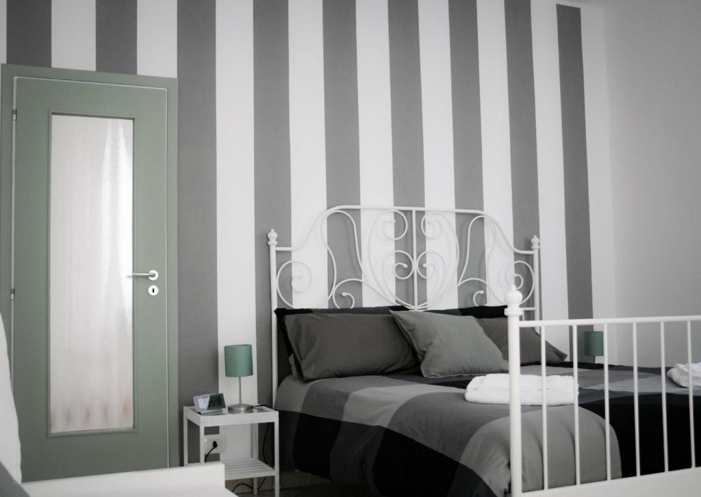 1 dormitorio con cama y pared a rayas en Le stanze di Alicam, en Arona