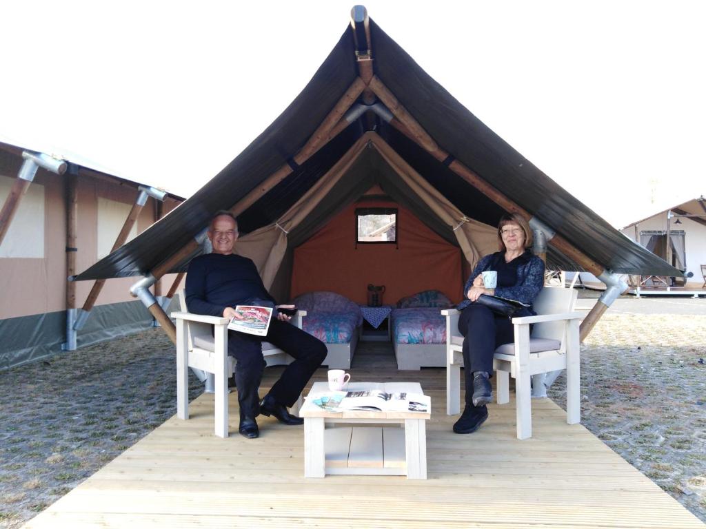 a man and woman sitting in chairs in front of a tent at Kamp Romantik - glamping in Labin
