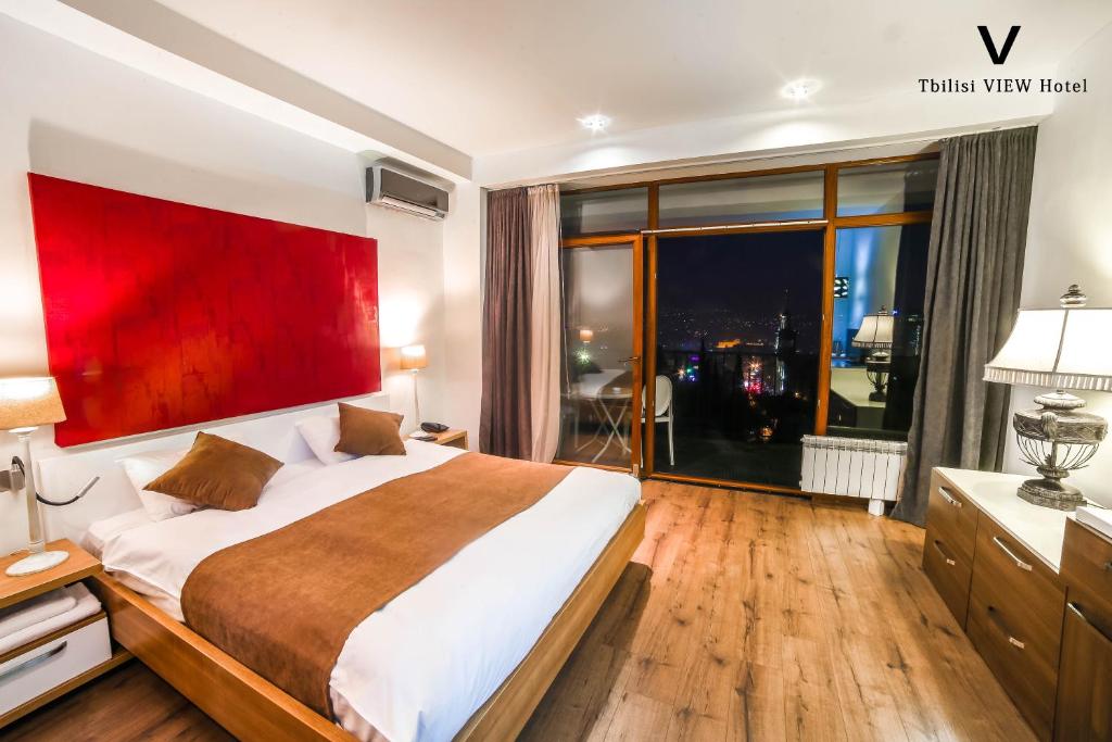 sypialnia z dużym łóżkiem i dużym oknem w obiekcie Tbilisi View Hotel w mieście Tbilisi City