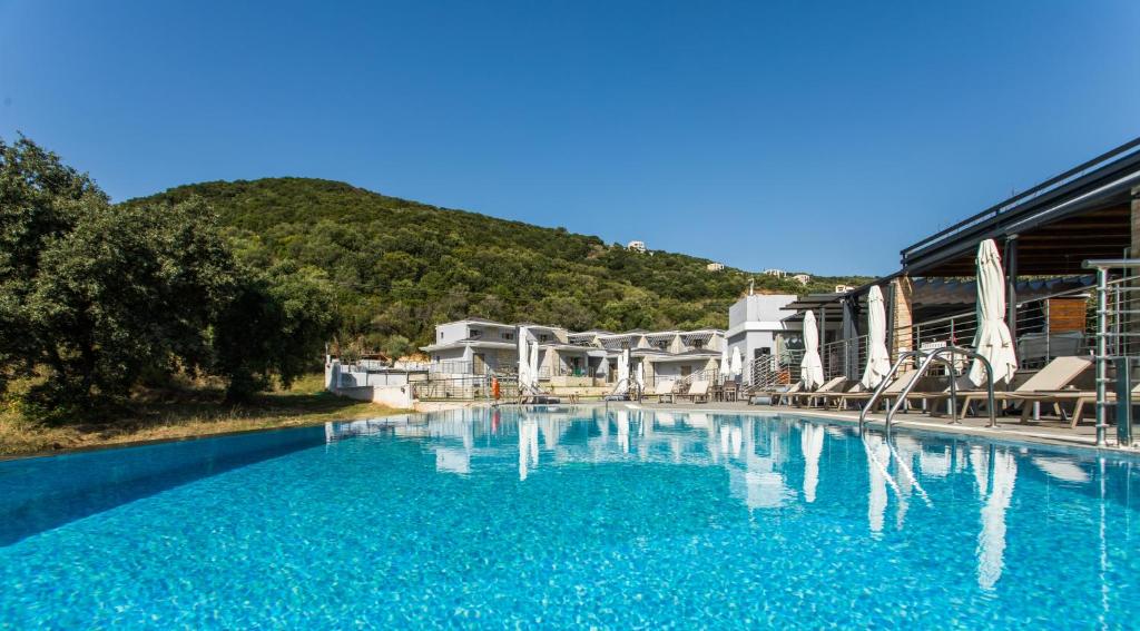 una gran piscina de agua azul frente a un edificio en Aqua Oliva Resort Syvota, en Sivota