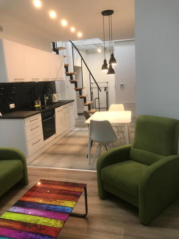 ボフニャにあるKlimatyczny apartament przy bocheńskim Rynku.のリビングルーム(緑のソファ付)、キッチンが備わります。
