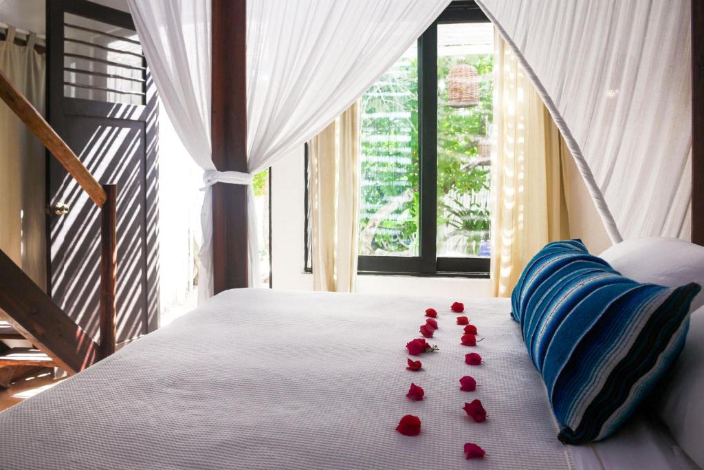 a bed with red rose petals on it at Casa Violeta in Tulum