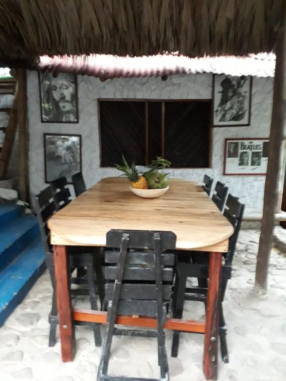 un tavolo di legno con sedie e una ciotola di frutta sopra di Hostel Cattleya a Palomino