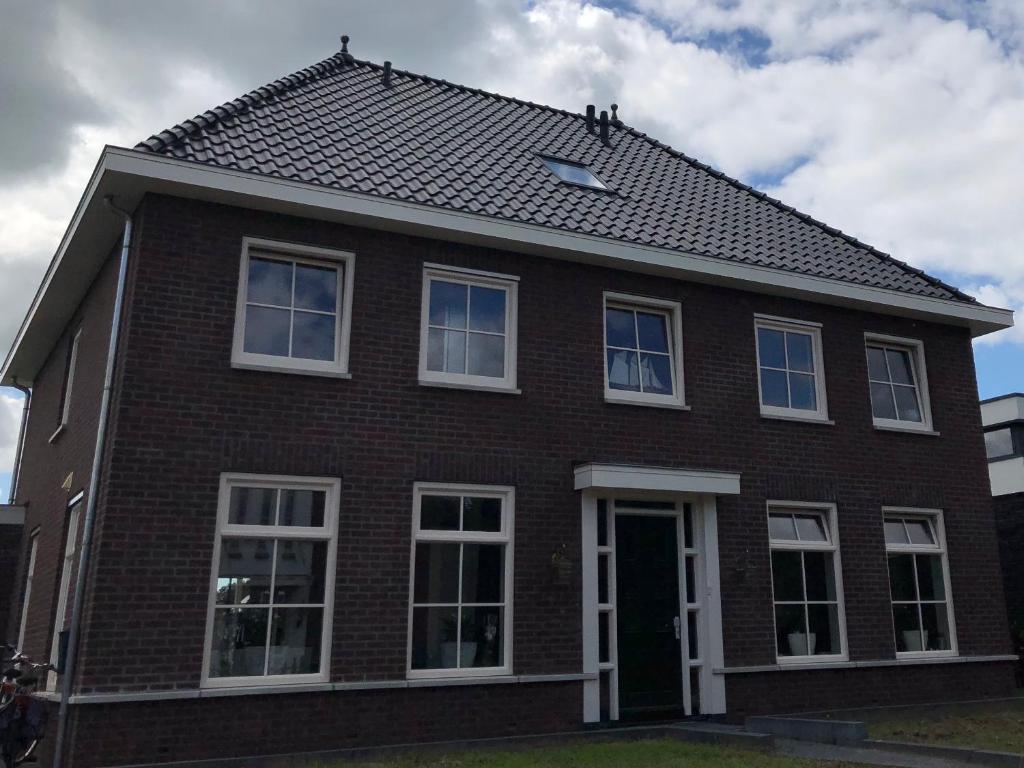 uma casa de tijolos castanhos com janelas brancas e um telhado em B&B nancy in holland em Aalten