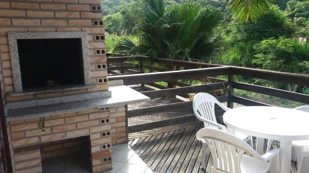 un patio con chimenea, mesa y sillas en Apartamento Bombinhas, en Bombinhas