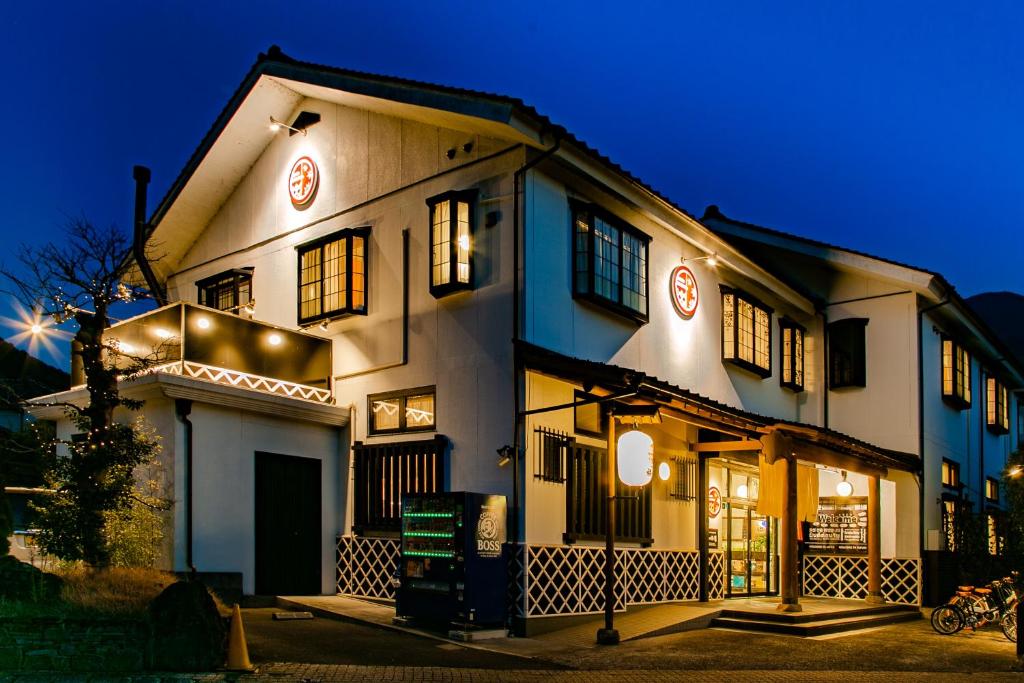 Un bâtiment blanc avec des lumières allumées la nuit dans l'établissement Yufuin Tabinokura, à Yufu