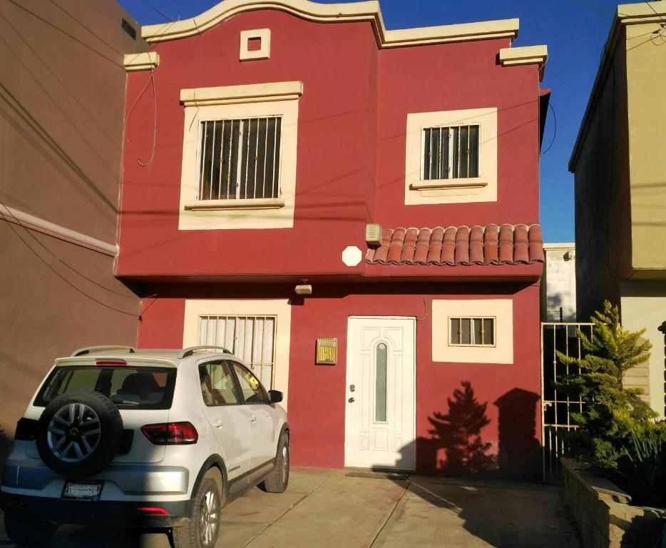 un coche blanco estacionado frente a una casa roja en Casa Gamboa, en Ensenada