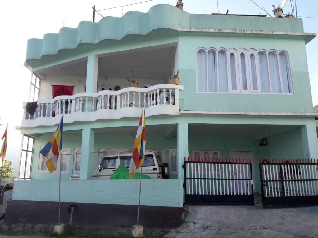a blue house with two flags in front of it at Bliss Homestay in Tawang