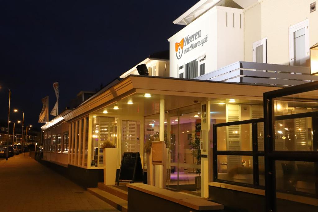 a building with glass windows on a street at night at Heeren van Noortwyck in Noordwijk aan Zee