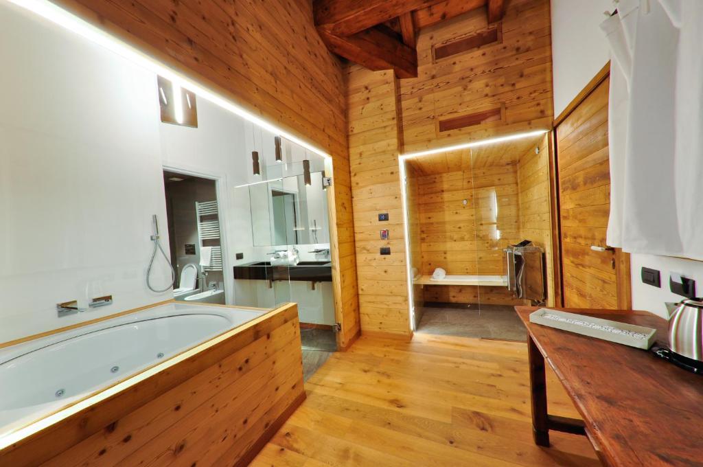 bagno con ampia vasca e parete in legno di Maison Bionaz Ski & Sport ad Aosta