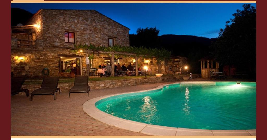 a swimming pool in front of a house at night at Ferme U San Martinu in Sisco