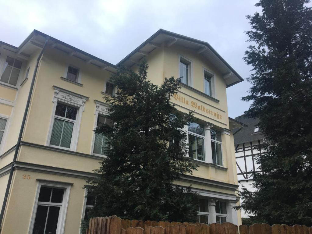 żółty budynek z drzewem przed nim w obiekcie Ferienvilla Waldstraße Wohnung Nr. 4 w mieście Bansin