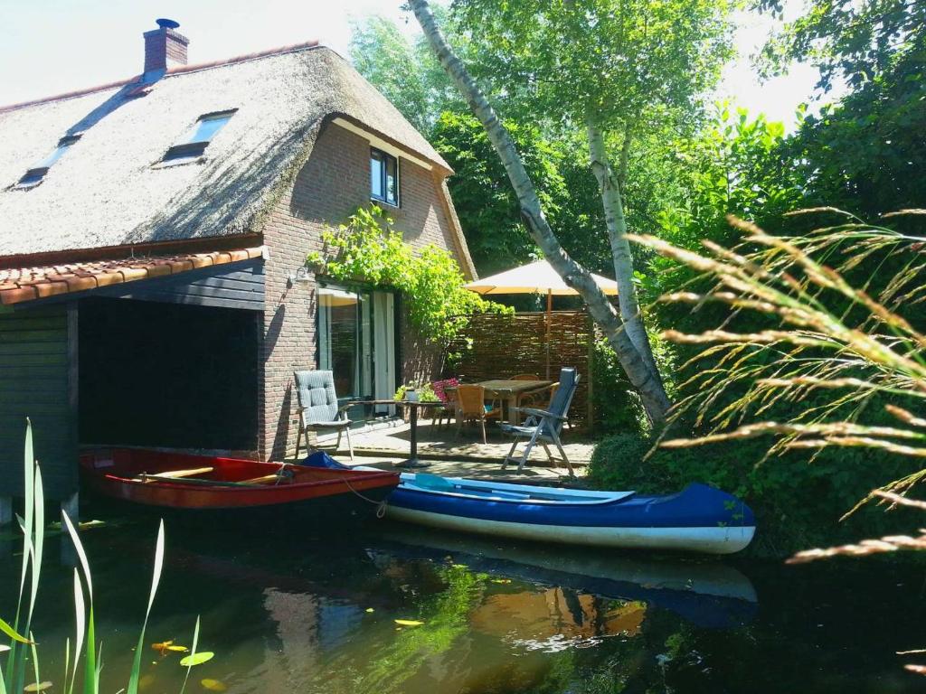 a house with two canoes in the water in front at Giethoorn Lodge in Giethoorn