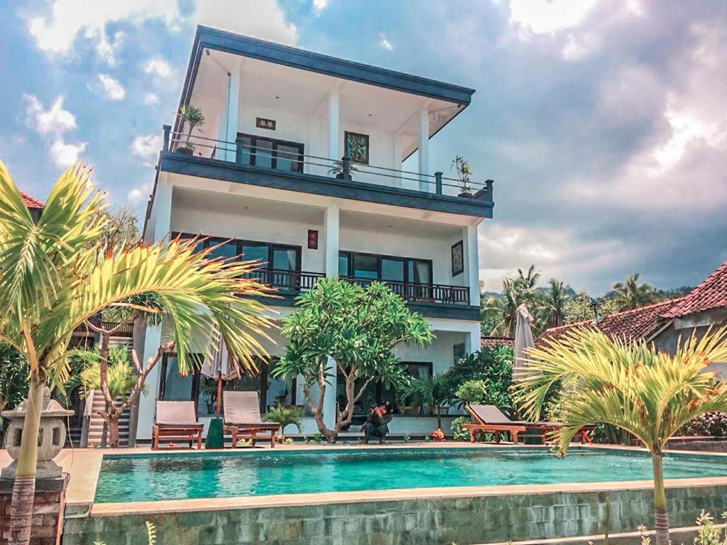 a house with a swimming pool in front of a house at Alam Bali Beach Resort in Amed