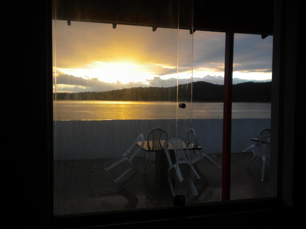 a view of a sunset from a window with a table and chairs at Cobertura paraiso Cacoes in Jaguaripe