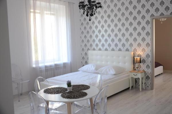 a bedroom with a white bed with a table and chairs at MULTI Apartment Łąkowa 18 in Białystok