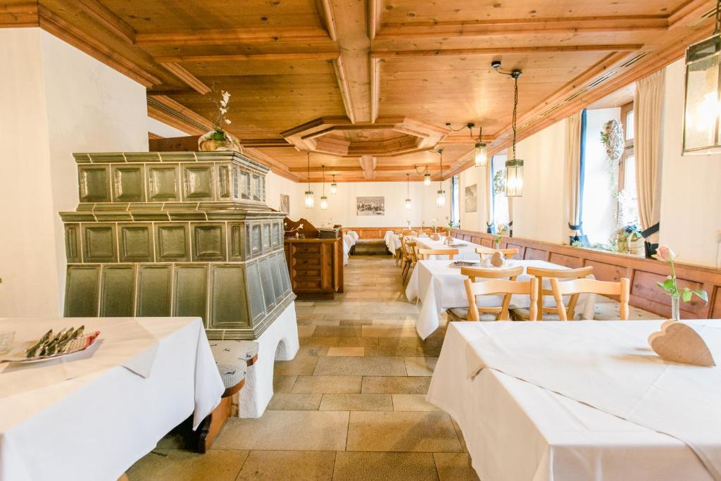 un restaurante con mesas blancas y techos de madera en Landgasthof zum Herz, en Trauchgau