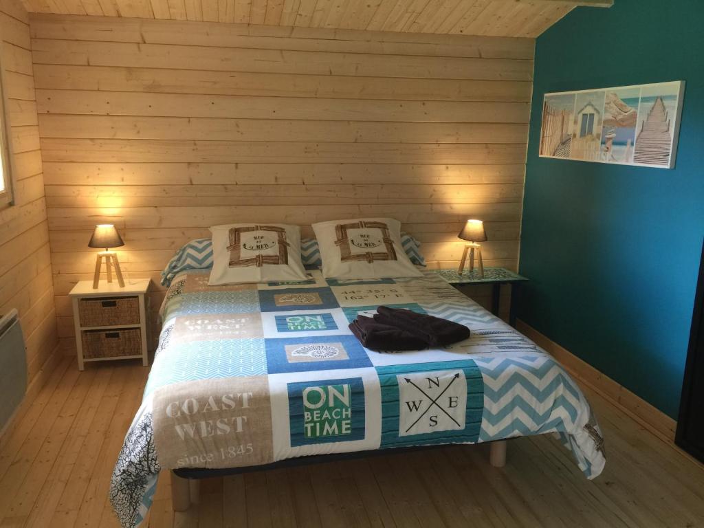 1 dormitorio con 1 cama con pared de madera en Maison de Lege, en Lège-Cap-Ferret