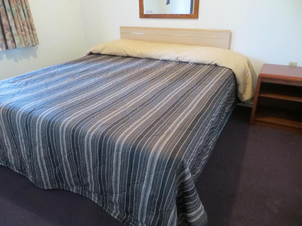 a bed with a blue and white striped comforter in a room at Madison Suites Motel in Portland
