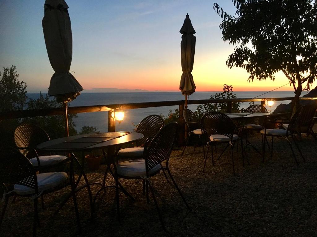 a group of tables and chairs with the sunset in the background at Villa Pietrafiore in Monterosso al Mare