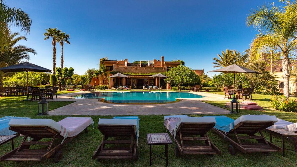 a swimming pool with chairs and a house at L'OLIVERAIE DE L'ATLAS in Marrakech