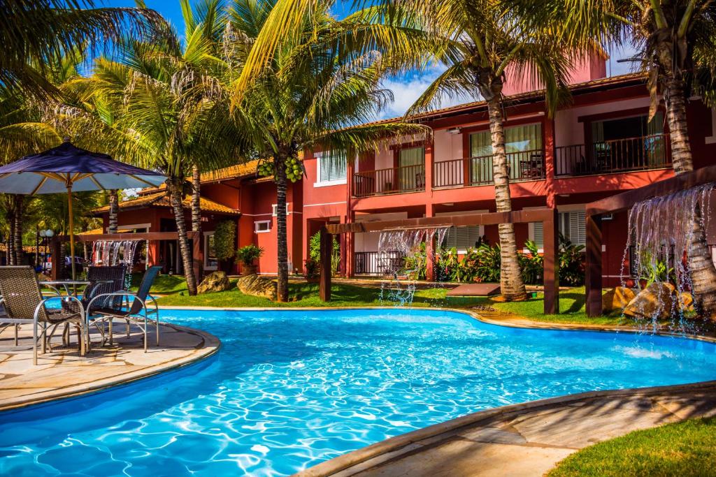 a pool in front of a hotel with palm trees at Balneário do Lago Hotel in Capitólio