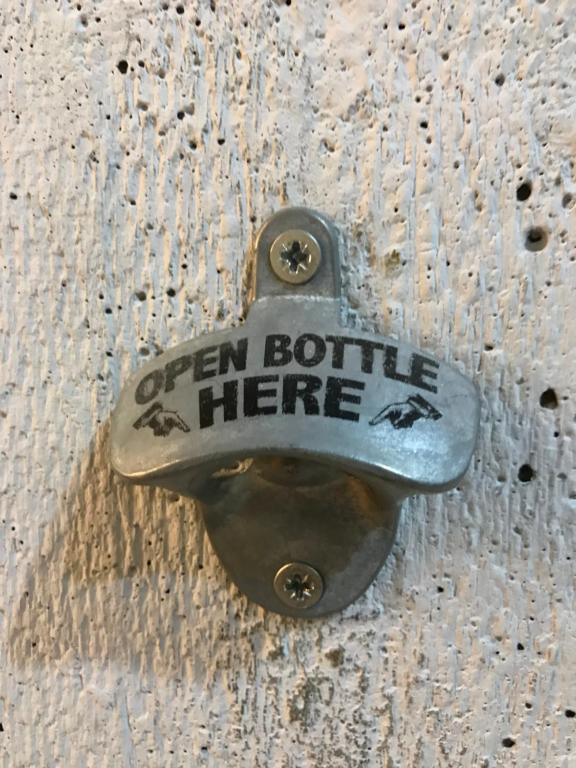 a metal doorhandle with a sign that reads open bottle here at T2&T3 Apartments LEVANTO in Tbilisi City
