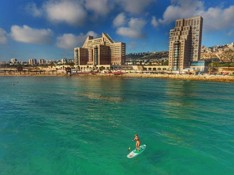 uma pessoa a montar uma prancha de surf no oceano com uma cidade em Rooms on the sea em Haifa