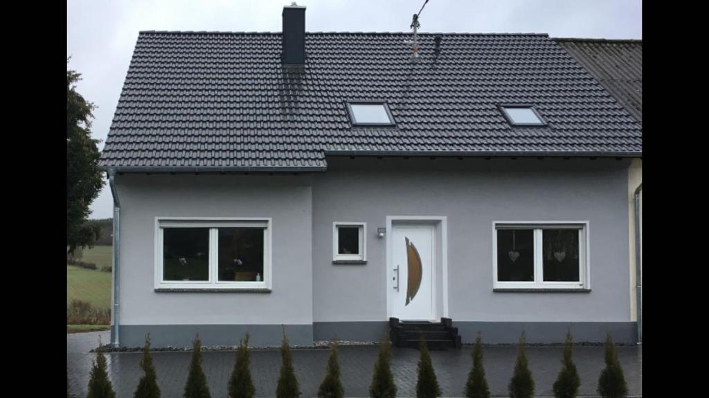a white house with a black roof at Ferienhaus Auf der Hill in Büdesheim