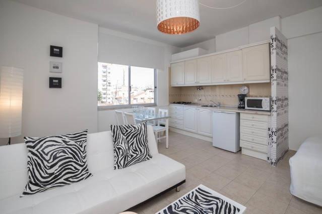 a white living room with a couch and a kitchen at In Bed with Lisbon 5E in Amadora