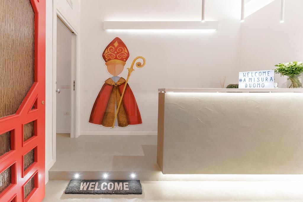 un cartello di benvenuto in una stanza con una bambola appesa a un muro di A Misura Duomo Rooms & Apartment - LS Accommodations a Napoli