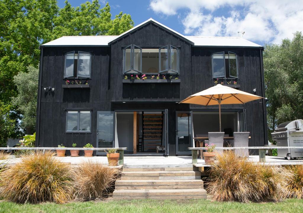 a black house with an umbrella in front of it at Black Walnut Cottage in Havelock North