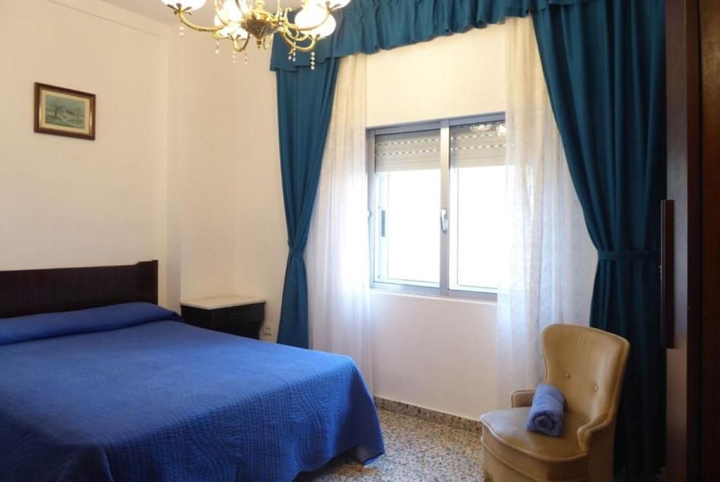 a bedroom with a blue bed and a window at El mirador del mar in Ferrol