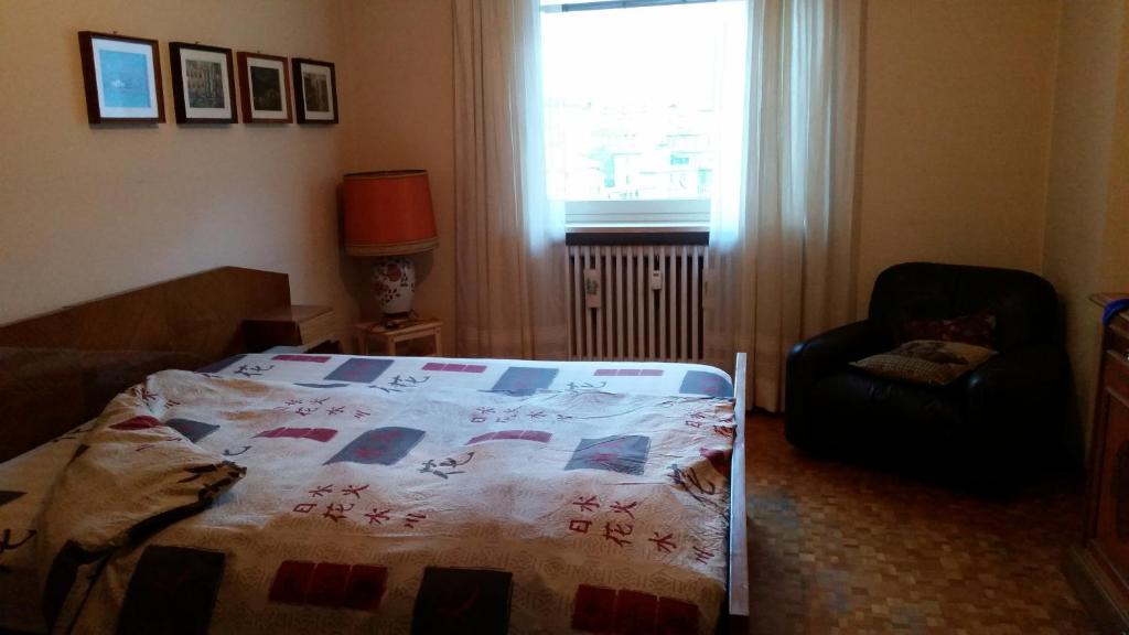 ein Schlafzimmer mit einem Bett, einem Stuhl und einem Fenster in der Unterkunft a due passi dalla neve in Perosa Argentina