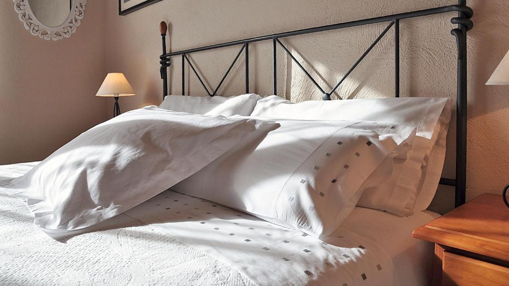 Cama blanca con sábanas y almohadas blancas en Casa Rural Rebost, en Sant Llorenç de Morunys