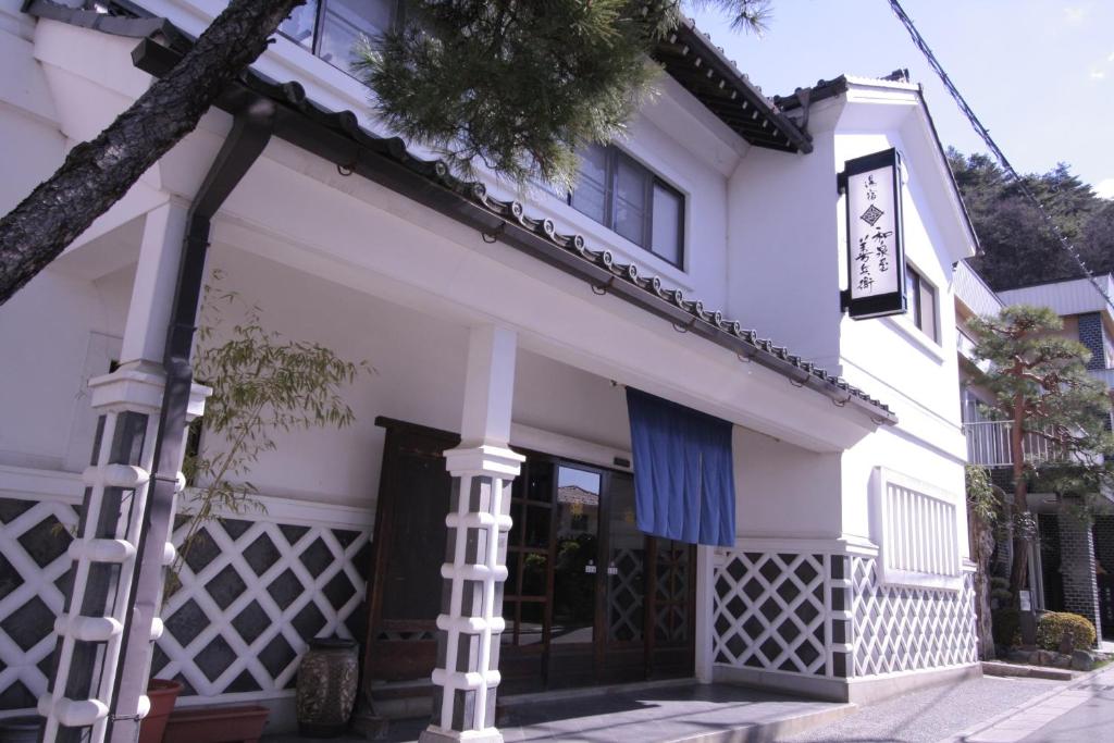 a white building with a sign on it at Izumiya Zenbe in Matsumoto