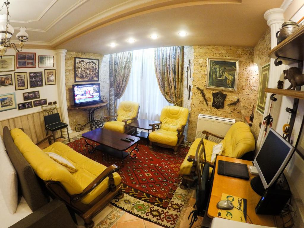 a living room with yellow furniture and a television at DB Apartment in Tirana