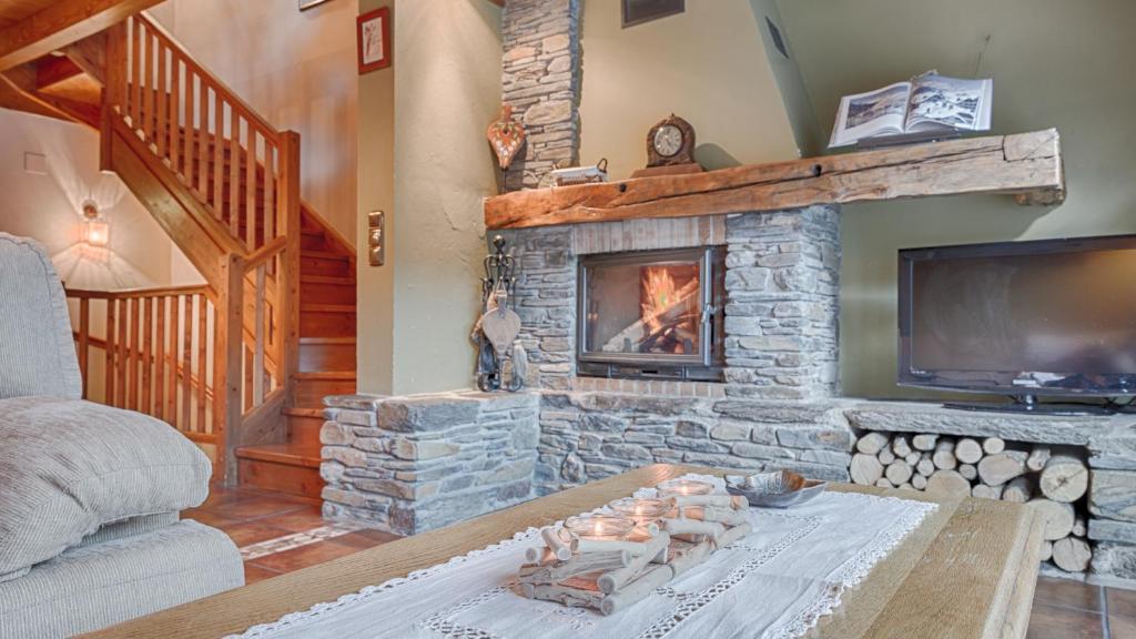 a living room with a stone fireplace and a tv at Casa Irissa in Vielha