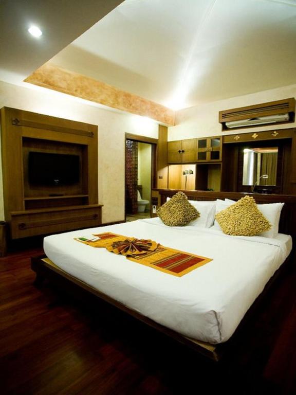 a bedroom with a large white bed with a television at Montien House - SHA Plus in Chaweng