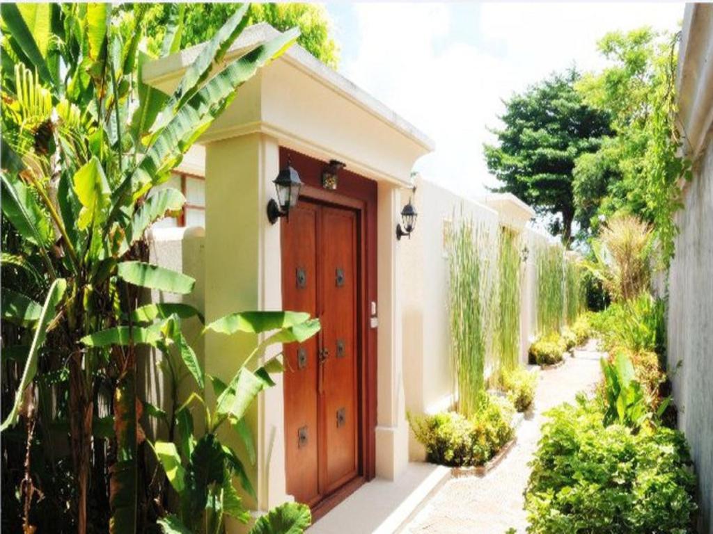 a house with a wooden door in a garden at Montien House - SHA Plus in Chaweng