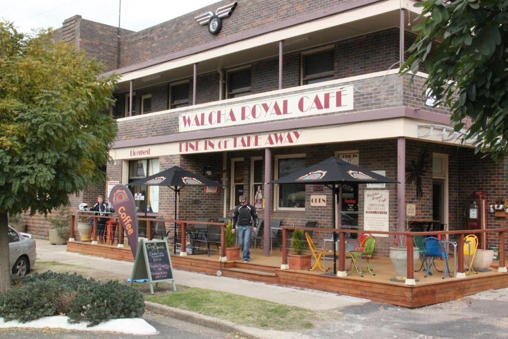 a man walking in front of a building with umbrellas at Walcha Royal Cafe & Accommodation in Walcha