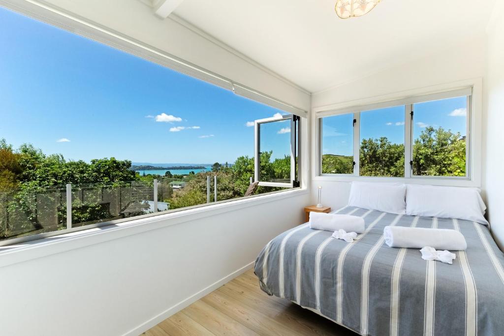 a bedroom with a bed and a large window at Tiri Cottage - Sea Views in Oneroa by Waiheke Unlimited in Oneroa