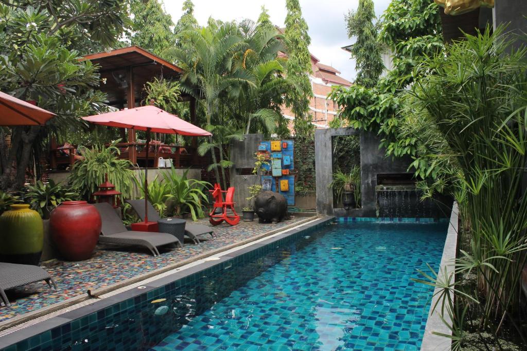 a pool in the middle of a resort with palm trees at Villa Thapae in Chiang Mai