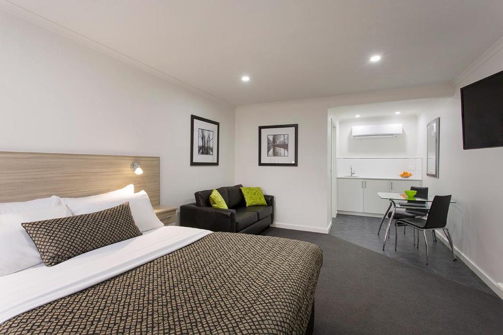 - une chambre avec un lit, une chaise et un bureau dans l'établissement Hamilton Lonsdale Motel, à Hamilton