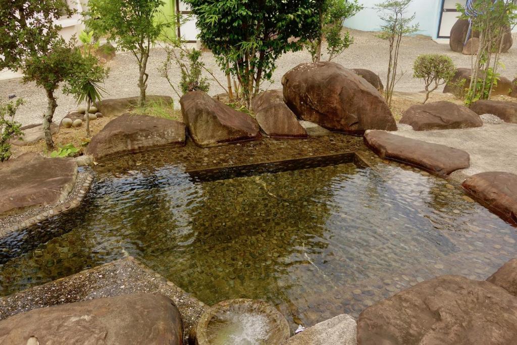 a pool of water with rocks in a garden at Seiryukyou in Nishinoomote