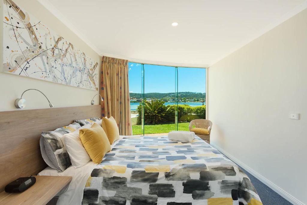 een slaapkamer met een bed en een groot raam bij Cetacea Luxury Apartments in Merimbula